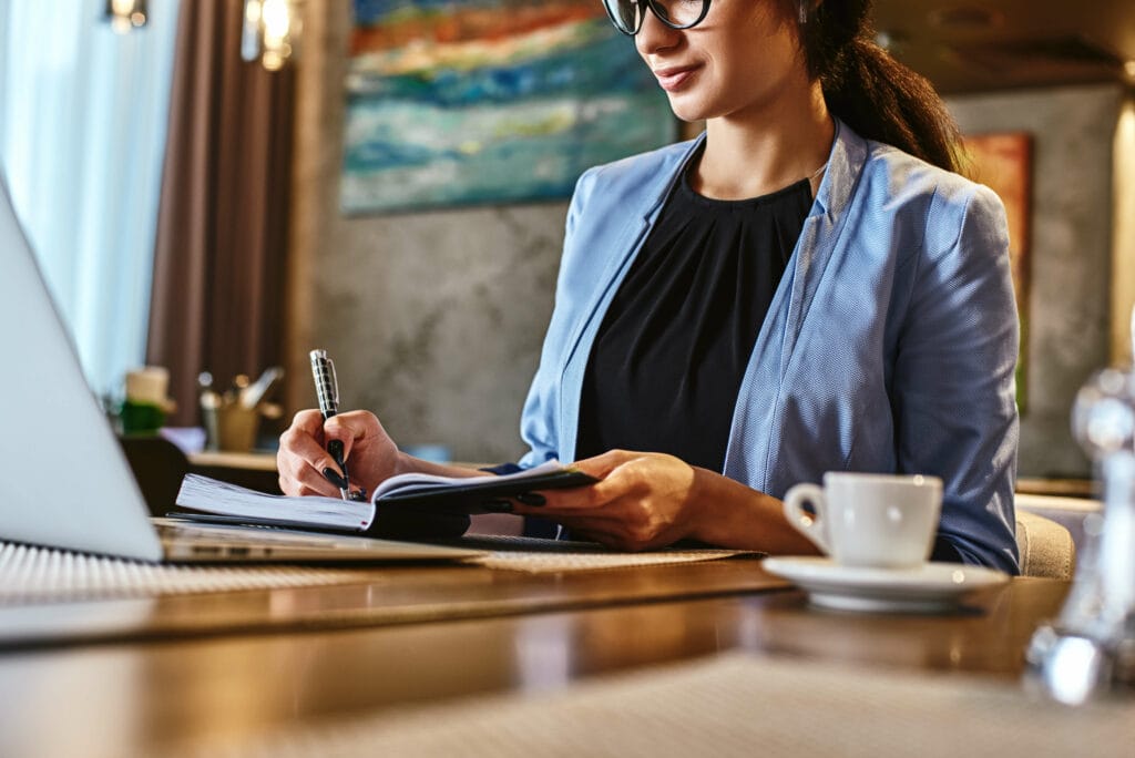 woman setting goals using notepad and laptop