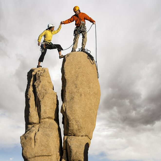 Man helping Woman climb a rock