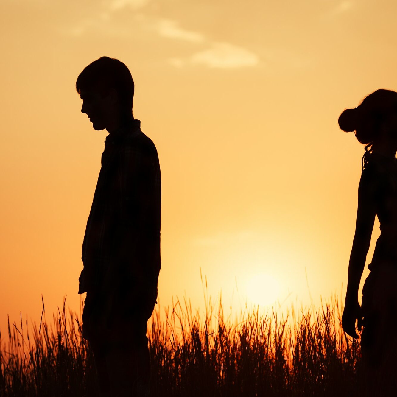 couple standing against the sunset back to back